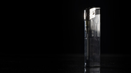 Closeup of a silver metal lighter isolated on a black reflective background