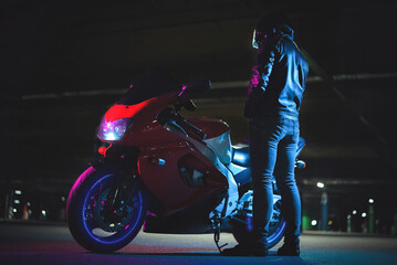 Motorbiker near his bike in the neon lights.