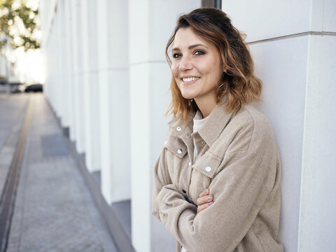 Happy attractive relaxed woman standing waiting on a street