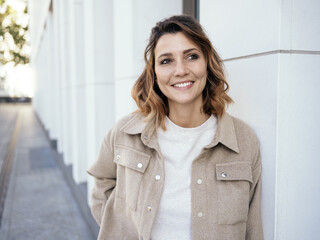 Relaxed friendly young woman standing on a street in town