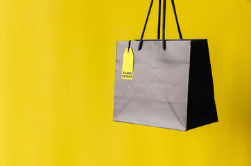 Black shopping bag with yellow price tag with yellow background for Black Friday shopping sale concept.