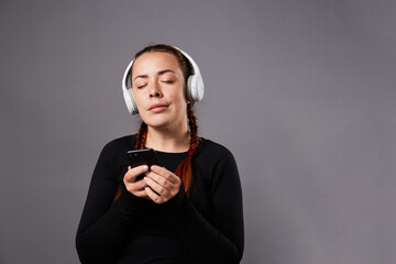 Close up portrait of caucasian female podcast or music listening on grey background. listening...
