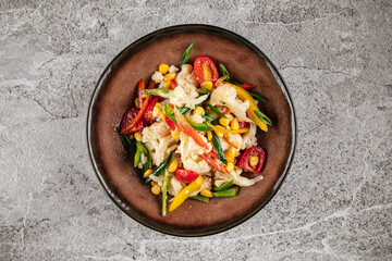Fresh healthy cauliflower salad with vegetables on gray background