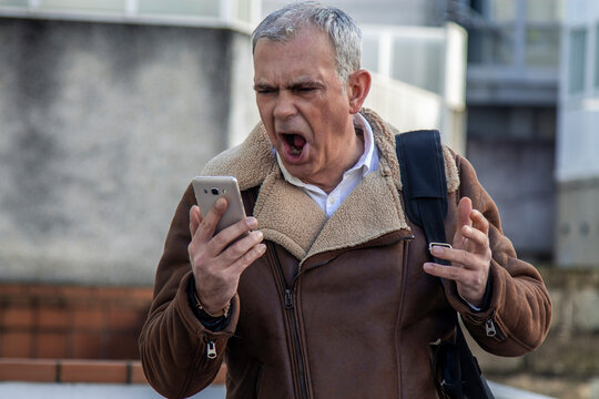 man screaming with his mobile phone and his laptop