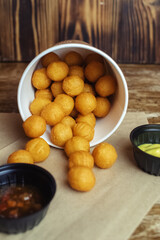 Close-up of potato balls prepared in a fast food restaurant. Barizl national cuisine. Food in a cardboard box. Takeout food. Round buns with potatoes and cheese.
