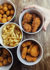 Top view of onion rings, cheese balls, chicken nuggets, wings in batter, fries and cheese sticks. Six-course set in paper buckets. Fast food cafes and restaurants. Food is laid out in shape of flower