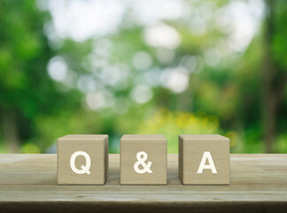 Q and A acronym on wood block cubes on wooden table over blur green tree in park, Frequently asked...