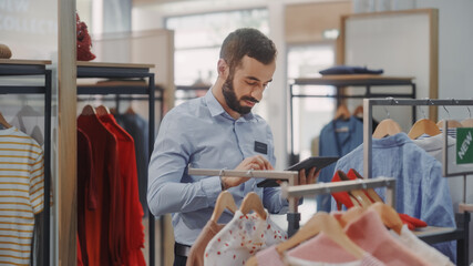 Clothing Store: Male Visual Merchandising Professional Uses Tablet Computer To Create Collection....