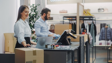Clothing Store Checkout Cashier Counter: Female and Male Retail Sales Managers Carefully Packing...