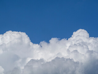 Naklejka na ściany i meble A huge white cloud against a clear blue sky. The natural background of the sky. Desktop wallpaper postcard, layout with space for text