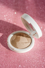 Beige blush on a pink shiny background.