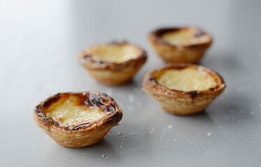 Egg tart, traditional Portuguese dessert, pastel de nata, pasteis on a plate. Grey stone background.