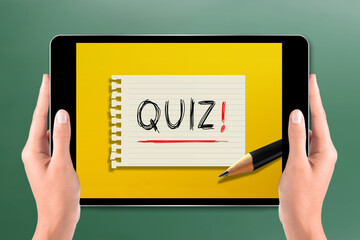 Hands holding digital tablet with quiz time concept on chalkboard