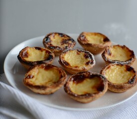 Egg tart, traditional Portuguese dessert, pastel de nata, pasteis on a plate. Grey stone background.
