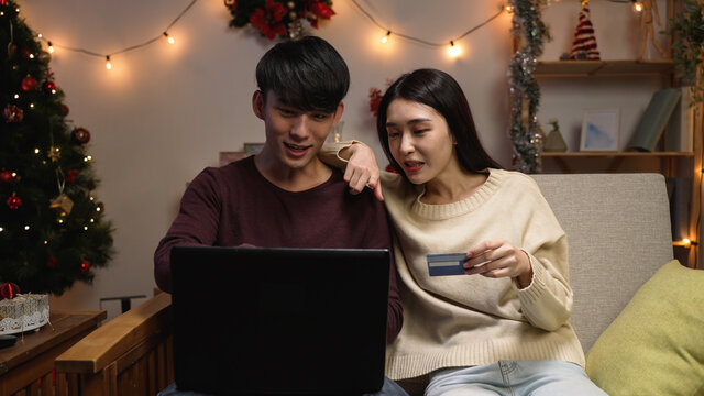 Happy smiling couple using credit card to internet shop online. Young lovers buying bargain things with special price on boxing day sale on pc. eshopping christmas and New Year Gifts at home