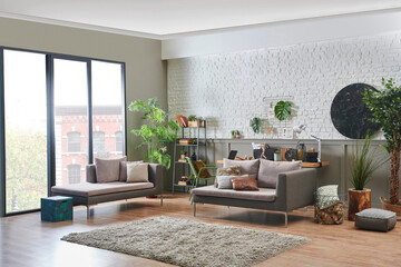 Modern living room sofa and working wood table style in the room, brick and brown classic wall background, grey bookshelf and accessory, laptop computer.