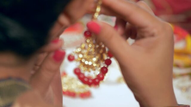 A young Indian bride wearing a beautiful earrings while getting ready. Fashionable jewelry collection displayed for sale on the counter of a jewelry store - glamor  luxury  lifestyle  makeup