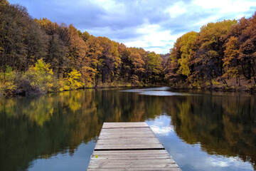 View of the lake in the autumn forest with blue water with wooden masonry