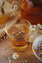 Glass of chamomile tea with honey and flowers on wooden table