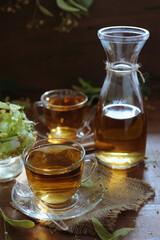 Hot herbal tea with linden flowers and honey on wooden background in sunshine