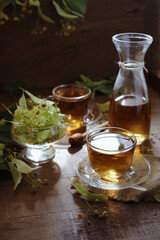 Hot herbal tea with linden flowers and honey on wooden background in sunshine