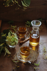 Hot herbal tea with linden flowers and honey on wooden background in sunshine