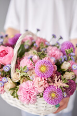 Flower arrangement in Wicker basket. Beautiful bouquet of mixed flowers in woman hand. Handsome fresh bouquet. Small flower shop and Flowers delivery.