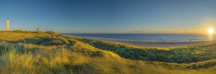 Sunset over dunes. Panoramic view of Blåvand lighthouse on wide dune of Blåvandshuk with beach view on the west coast of Jutland, by Esbjerg, Denmark.   - obrazy, fototapety, plakaty
