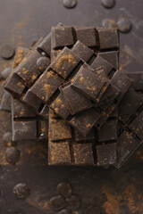 Bars, chopped and chips of dark chocolate on brown background