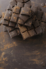 Bars, chopped and chips of dark chocolate on brown background