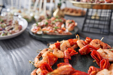 Delicious fresh seafood, shrimp with fresh vegetables. buffet table with lots of delicious snacks. canapes, bruschetta, and little desserts on wooden plate board