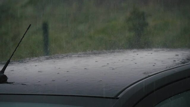 Shower flows falling and splashing on car roof in rainy weather in autumn 