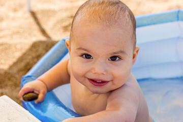 Happy smiling baby boy in an inflatable pool