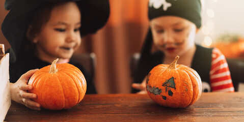 Children in witch and pirate costumes holding pumpkins in their hands