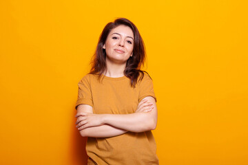 Obraz premium Confident woman standing with crossed arms in front of camera. Portrait of young person posing with casual expression and smiling, standing over isolated background in studio.
