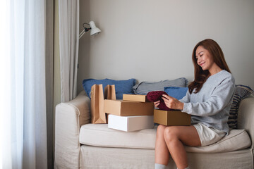 A woman receiving and opening a postal parcel box of clothing at home for delivery and online shopping concept