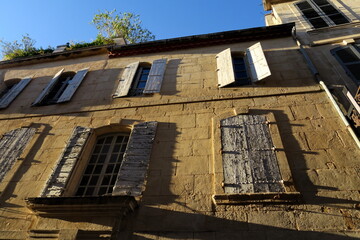 Fototapeta na wymiar Vieille maison aux murs jaunes avec volets en bois au soleil. Sud de la France.