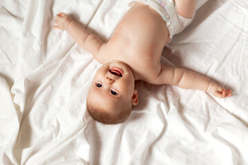 newborn baby in a diaper is lying on his back on a white sheet. products for children, toy. concept...