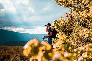 handsome man trekking in nature using binoculars slow travel