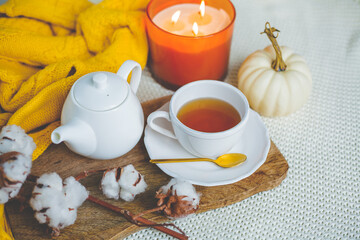 Autumn mood. A cup of hot cappuccino, pumpkins, knitted yellow plaid on a wooden stand. A branch of cotton. copy space.