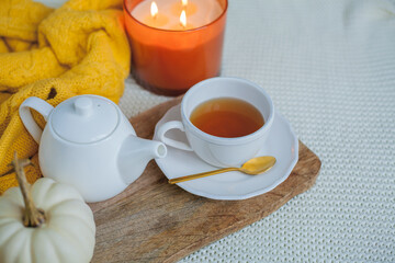 Autumn mood. A cup of hot cappuccino, pumpkins, knitted yellow plaid on a wooden stand. A branch of cotton. copy space.