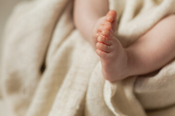 closeup bare children's feet of baby lying on a bed covered with a white sheet made of natural fabric. products for children. concept of happy childhood and motherhood. child care. space for text