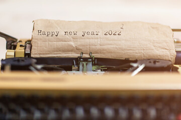 vintage typewriter with a brown sheet of paper and "Happy new year 2022" written on it.