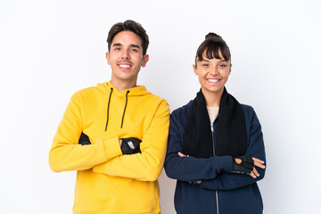 Young mixed race sport couple isolated on white background keeping the arms crossed in frontal...