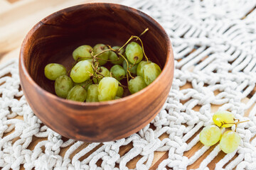geren grapes in wooden bowl on top of wooden dining table, simple ingredients concept