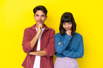 Young mixed race couple isolated on yellow background smiling and looking to the front with confident face