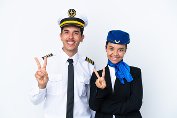Airplane pilot and mixed race air hostess isolated on white background smiling and showing victory...
