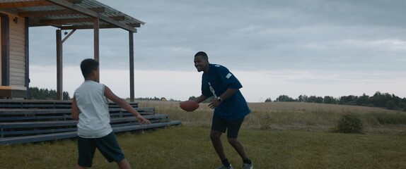 African American father and son playing together on a lawn in front of their house in the evening