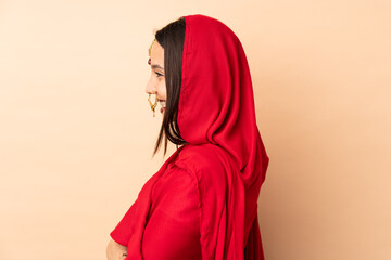 Young Indian woman isolated on beige background in lateral position