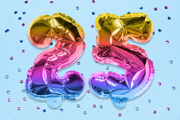 Rainbow foil balloon number, digit twenty five on a blue background with sequins. Birthday greeting card with inscription 25. Anniversary concept. Numerical digit. Celebration event, template.